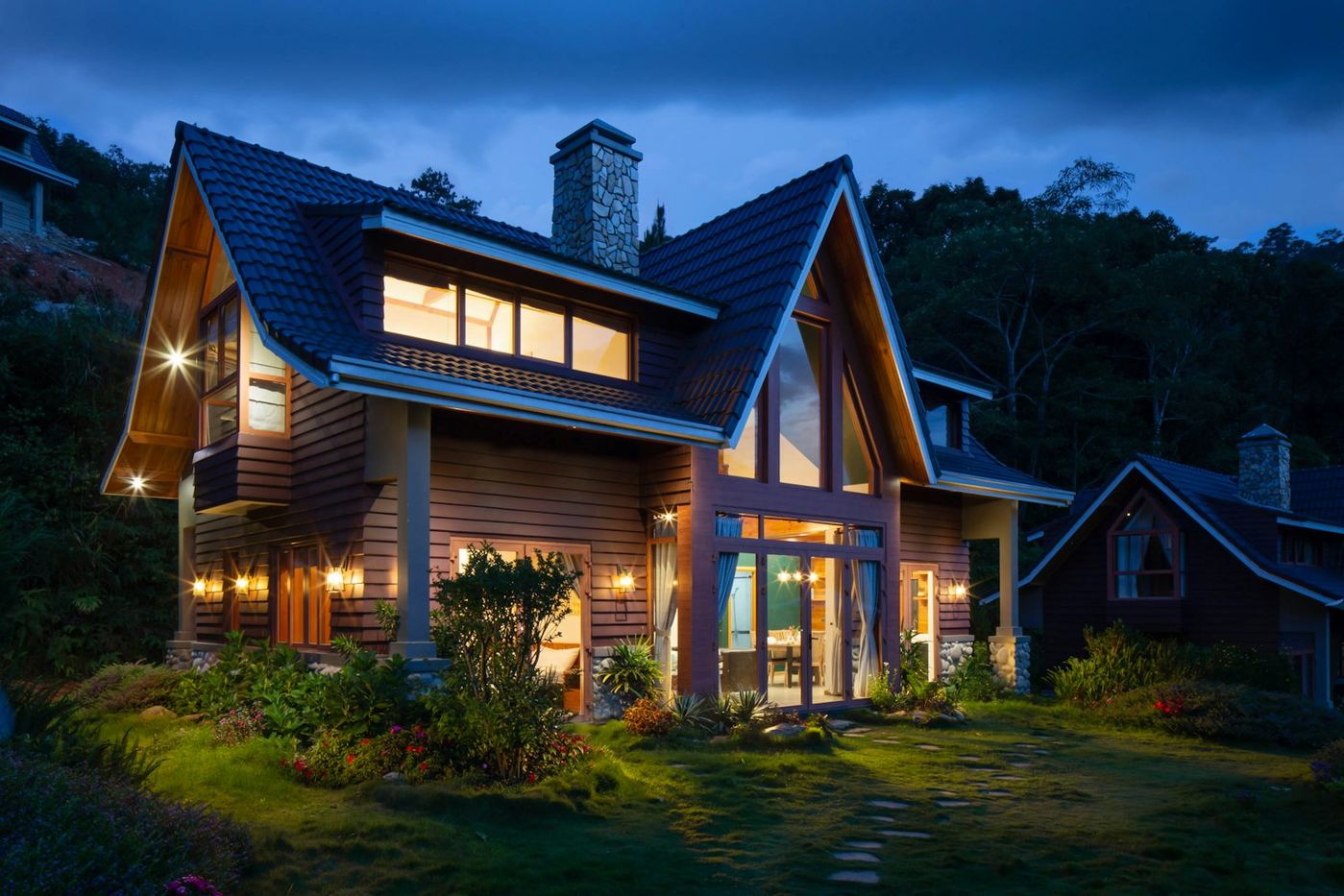Craftsman-style family home with a warm wood exterior and glowing windows at dusk.